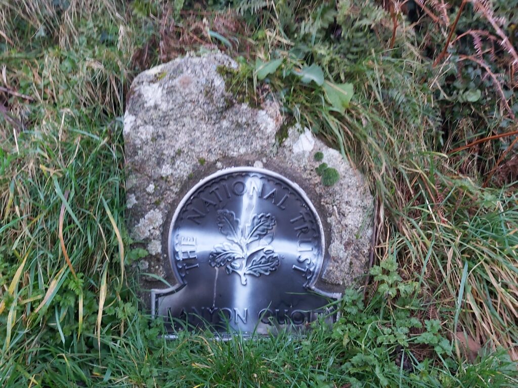 the Cornish Flag of St Piran (white cross on black background) spray painted onto a National Trust location marker stone at Lanyon Quoit